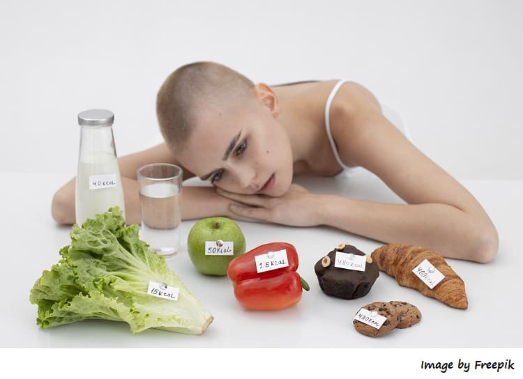 Mujer joven con trastorno alimentario junto a alimentos con numero Kcal
